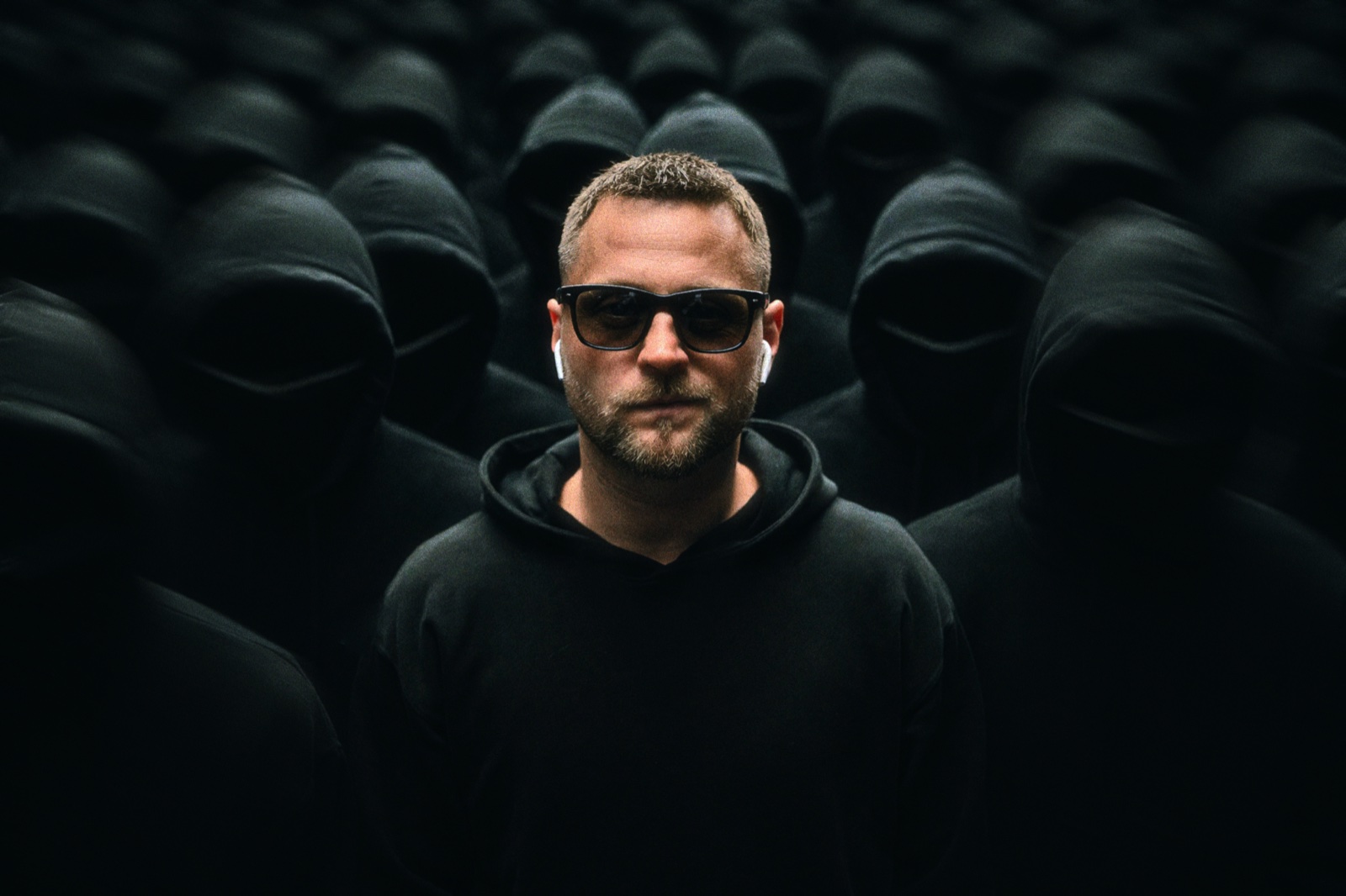 Serge Black inmitten anonymer Hoodie-Figuren